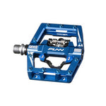 Close-up of a Funn Mamba S SPD Pedal, showcasing its blue, square-shaped design with metal studs and threaded attachment, ideal for enduro racing.