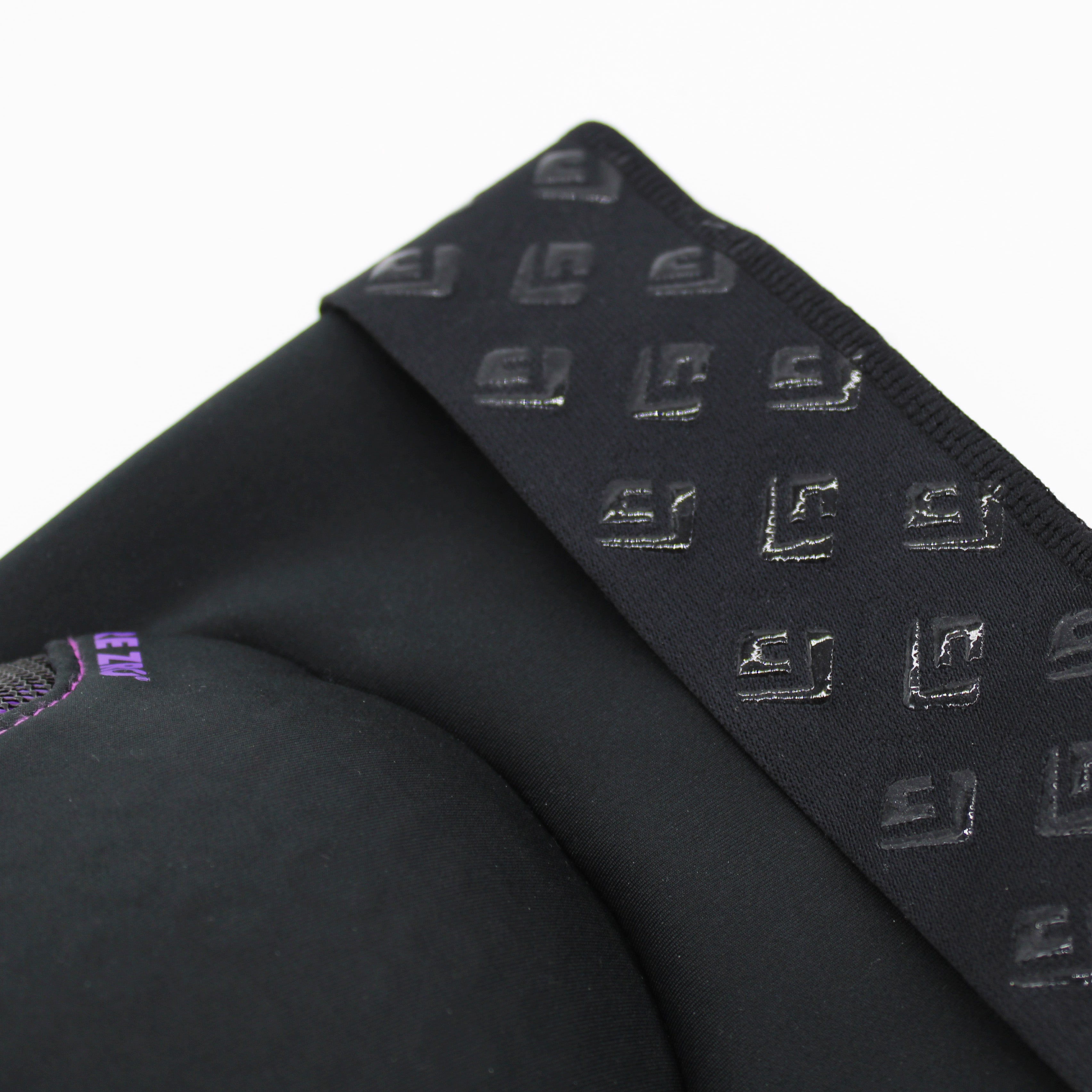 Close-up of a black fabric with textured rubber patterns and neoprene, featuring a partially visible purple text logo and enhanced impact protection. Ideal for those wearing G-Form RE ZRO Terra Elbow Guard or similar gear.