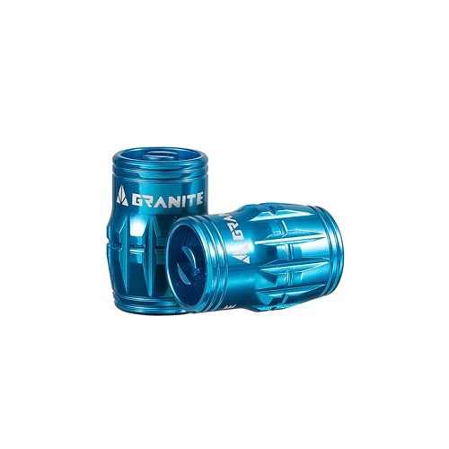 Two blue metallic cylindrical objects with grooves labeled "Granite Juicy Valve Caps w/ Valve Tool (Pair)" are stacked on a white background, likely serving as bike accessories for a tubeless setup.