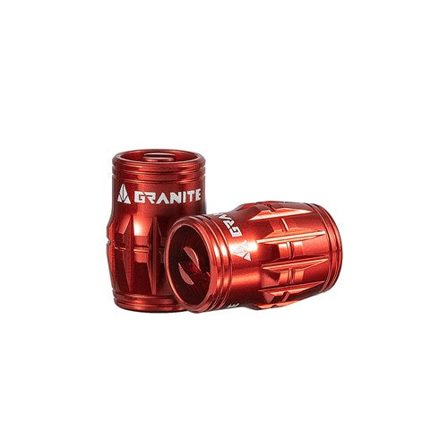 Two red cylindrical Granite Juicy Valve Caps with white text feature indented patterns, appearing like tools used for a tubeless setup.