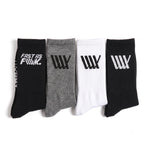 Four pairs of LUXBMX Crew Socks (4 Pack Mix)—in black, gray, white, and black—are displayed side by side, each showcasing striking graphic logos or text on the cuffs. Crafted for both comfort and durability, these crew socks are perfect for BMX riders who want a blend of style and performance.