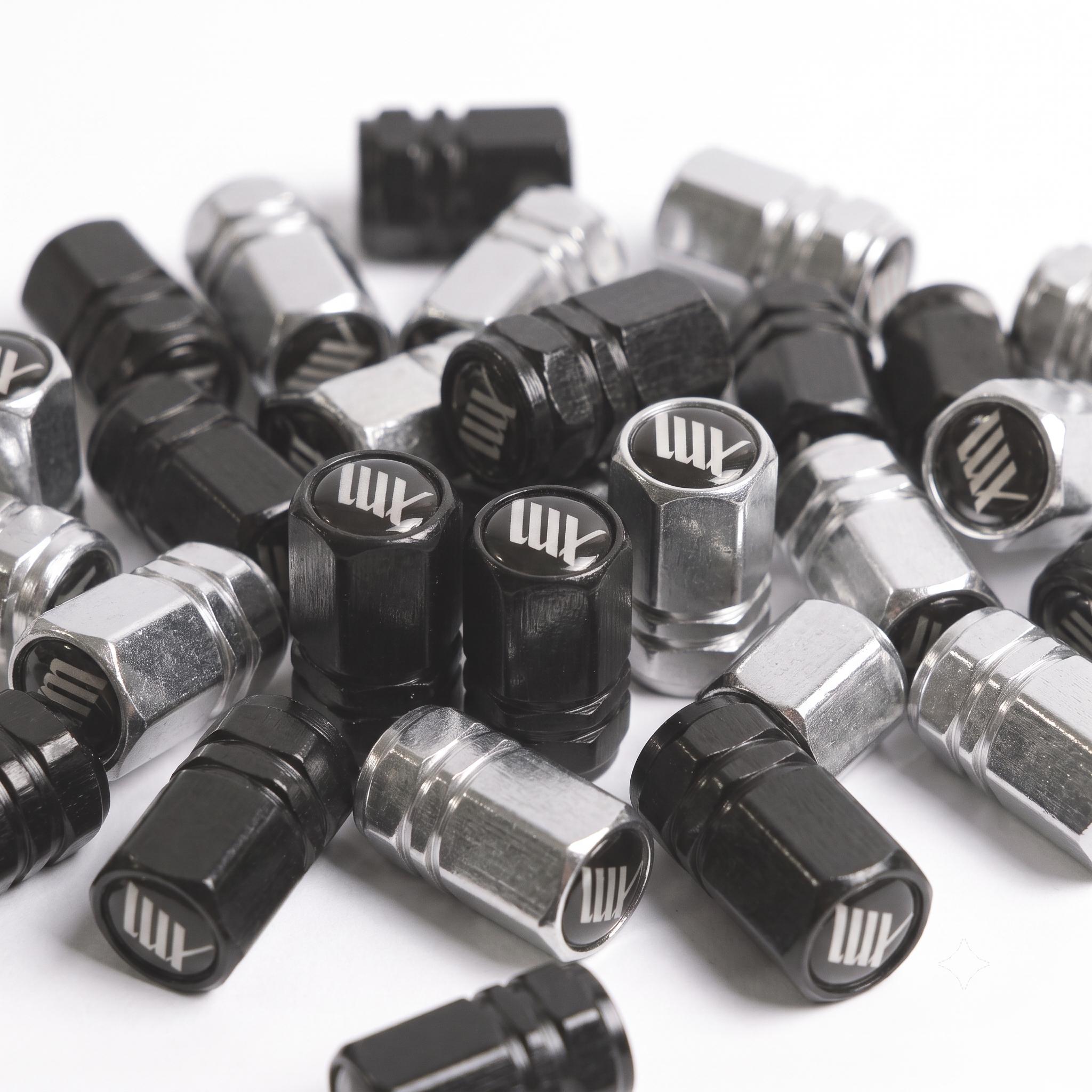 A pair of LUXBMX Hex Logo Alloy Valve Caps, featuring a black and silver machined finish and white "AM" logo—premium accessories perfect for adding custom style to your BMX ride.