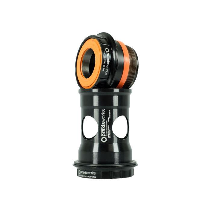 A Praxis Works BB30-PF30 24mm Bottom Bracket Kit in black and orange, prominently displaying its branding, is positioned vertically against a white background.