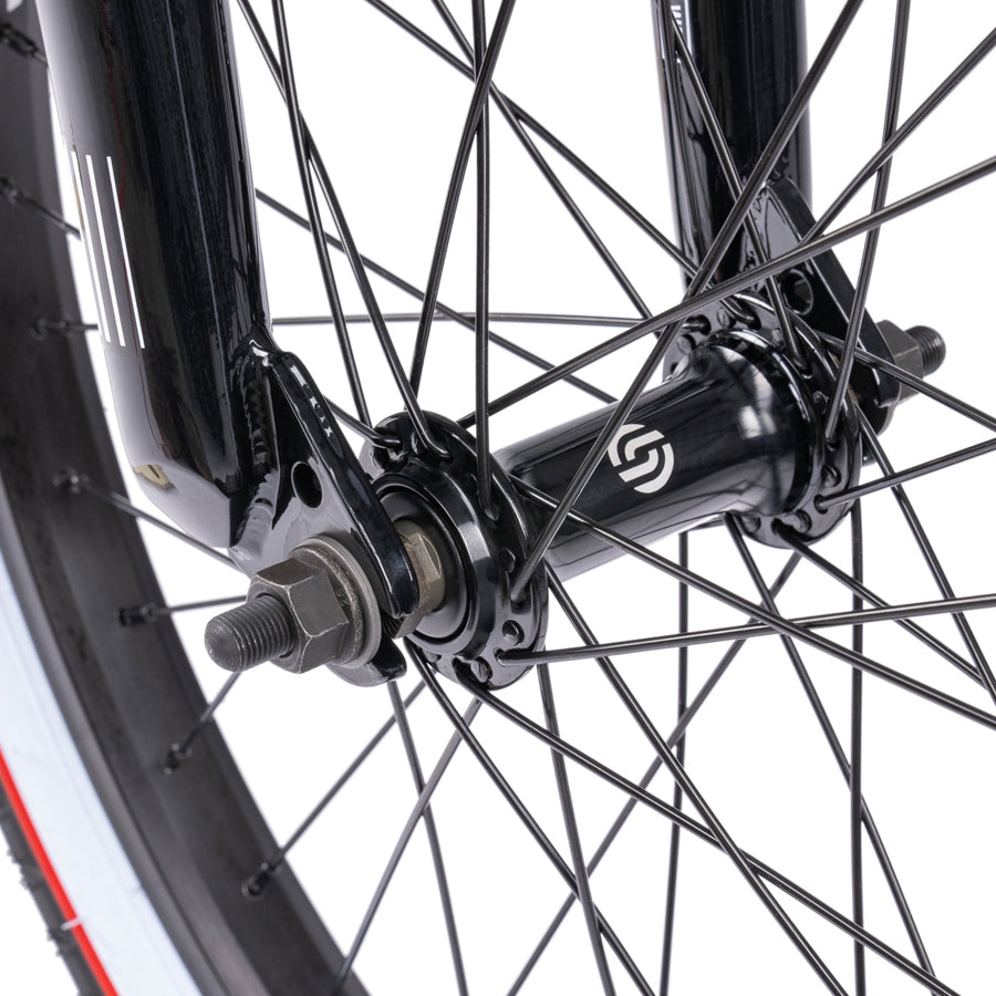 A close up of a black Wethepeople Nova 20 Inch BMX Bike wheel with red spokes featuring "Salt Rookie Tubular Chromoly Three Piece Cranks".