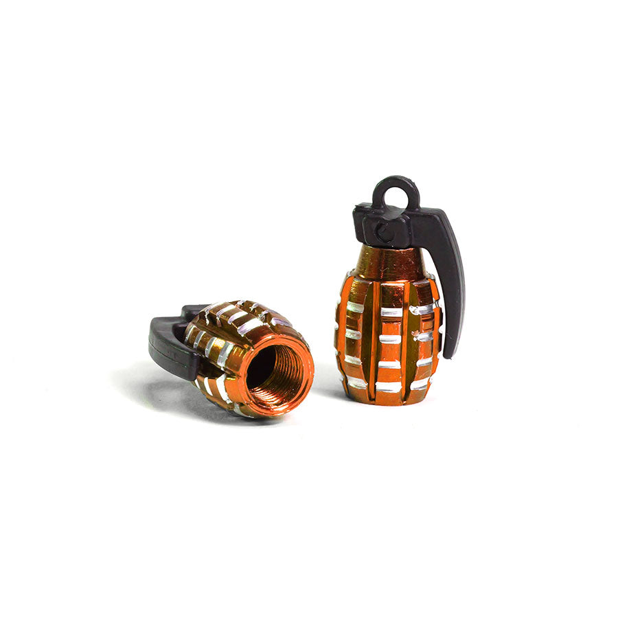 A pair of metallic Grenade Valve Caps in silver and copper colors—one stands upright with a black lever, while the other lies on its side displaying a Schrader valve threaded opening.