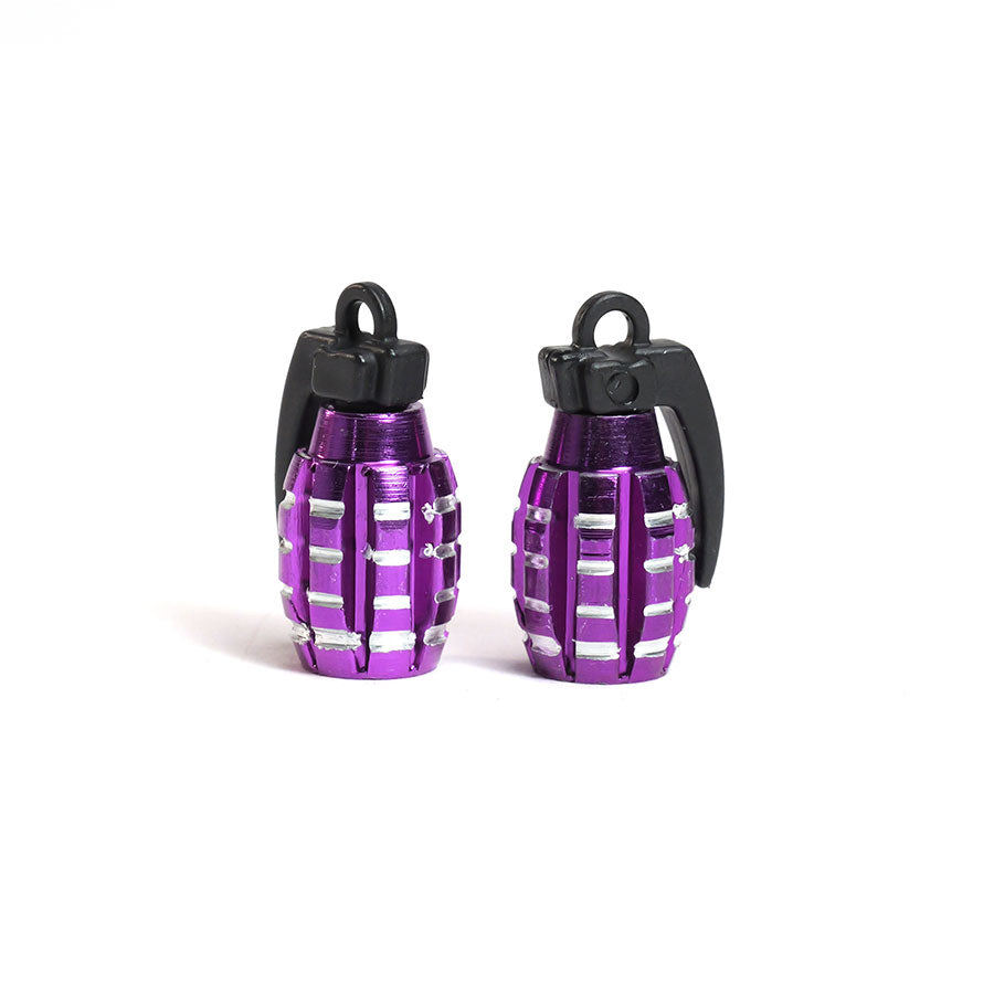 A pair of small, purple Grenade Valve Caps with black pull rings and silver accents—styled like grenades—are shown standing upright on a white background.