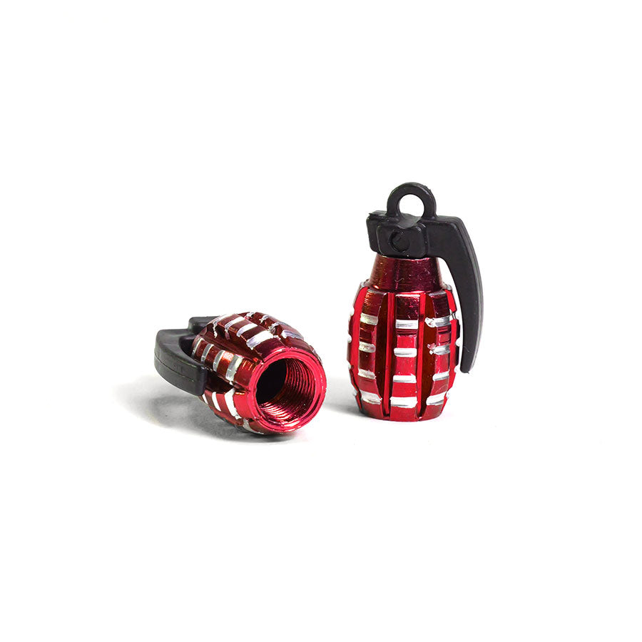 Two small, metallic red Grenade Valve Caps (Pair) with black tops—one standing upright, the other on its side—isolated on a white background.