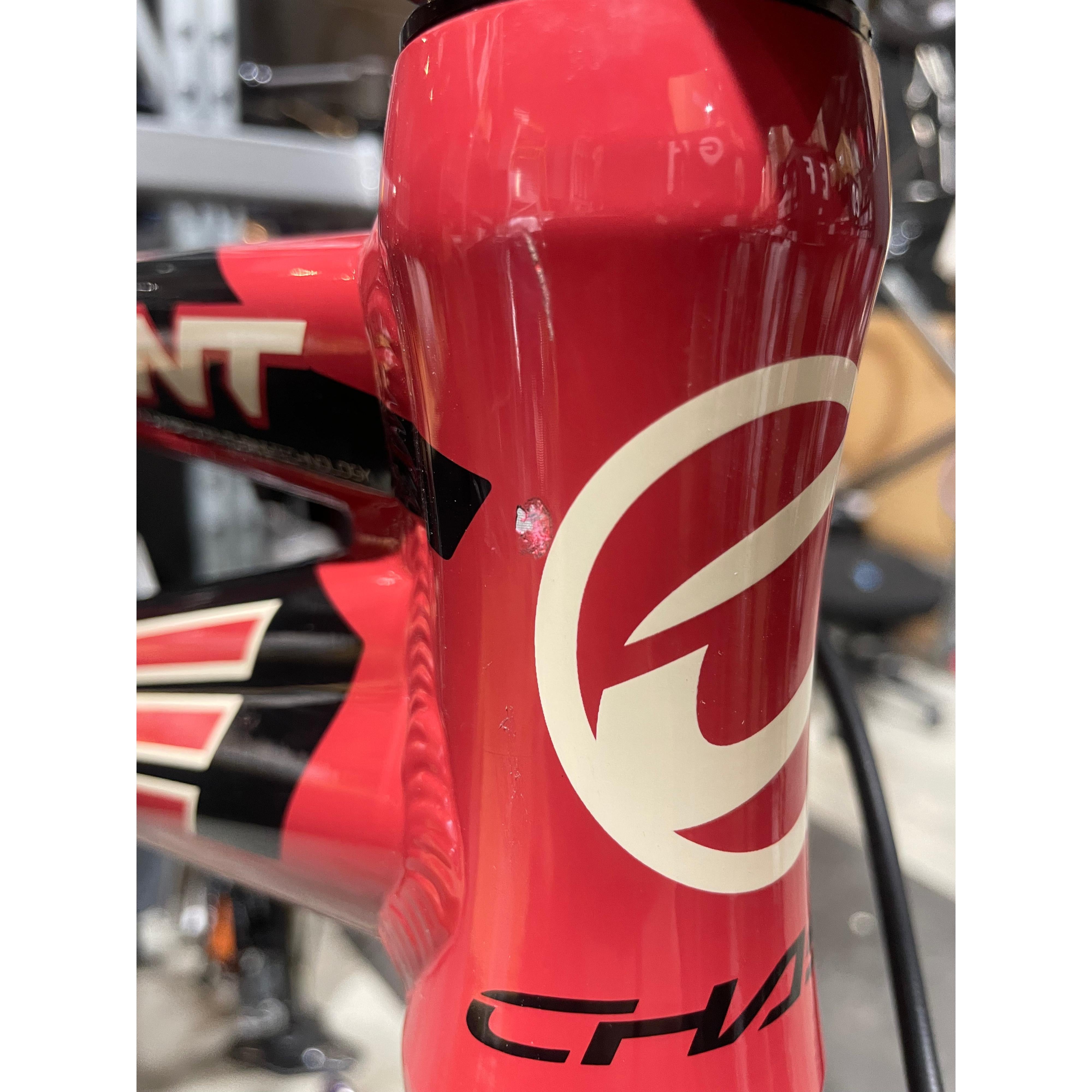 Close-up of a red Chase Element Pro XXXL Bike *scratch and dent* frame showing a noticeable paint chip with visible white underlayer near the white logo, black design accents, and Ikon carbon forks.