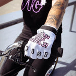 A tattooed rider grips handlebars, wearing YTG x Fist Lil' Fist Gloves—bold BMX gloves featuring "YEAH THE GIRLS!" and "FIST" in striking lettering.