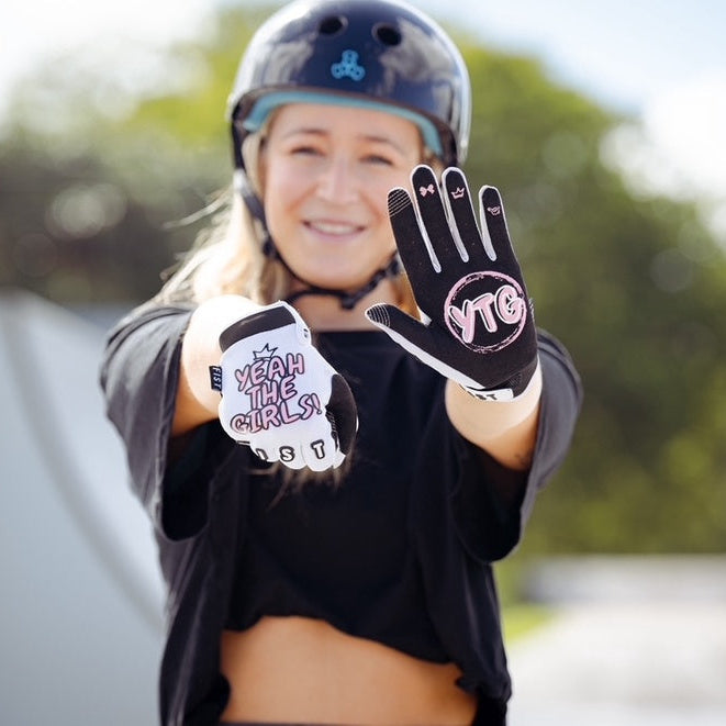 Wearing a helmet, a woman proudly displays her YTG x Fist Lil' Fist Gloves—one glove reads “YTG” and the other “Yeah The Girls.”.