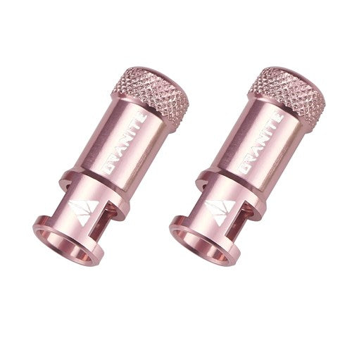 Two Granite Juicy CNC Presta Valve Caps with valve core removers, finished in metallic rose gold with textured tops and engraved logos, are displayed on a white background.