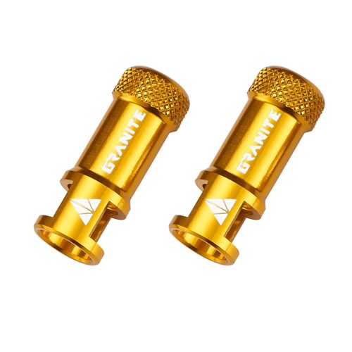 Two gold-colored Granite Juicy CNC Presta Valve Caps with built-in valve core removers are displayed side by side on a white background. Designed for Presta bicycle valves, these essential caps offer reliable protection and convenient on-the-go maintenance.
