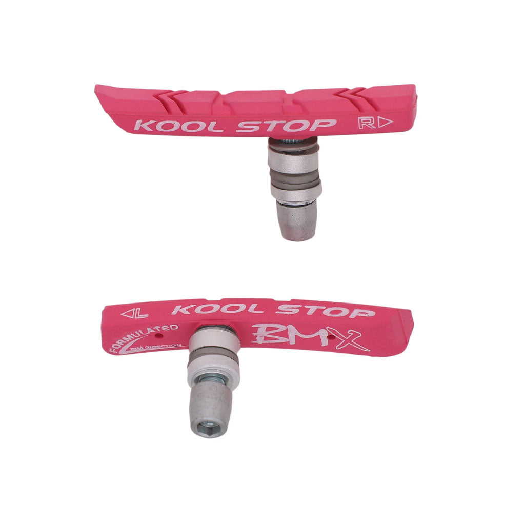 Two Kool Stop BMX Brake Pads in pink, each featuring a metal attachment base and branded text on the rubber surface, designed to enhance brake performance on BMX bikes with direct pull brakes.