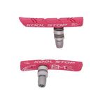 Two Kool Stop BMX Brake Pads in pink, each featuring a metal attachment base and branded text on the rubber surface, designed to enhance brake performance on BMX bikes with direct pull brakes.