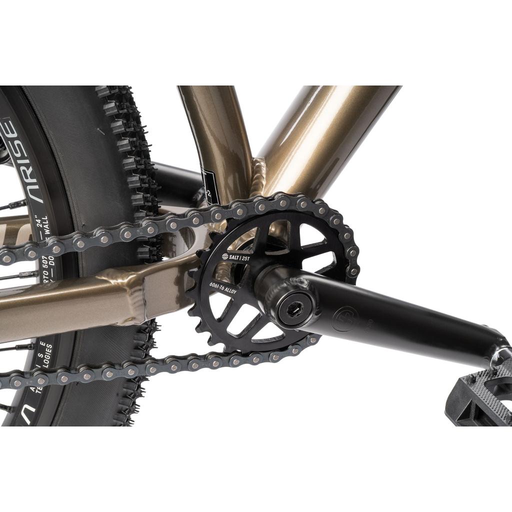 Close-up of the Radio Griffin 24 Inch Dirt Jumper Bike drivetrain, highlighting the chain, black crank arm, chainring, and part of the rear tire on its aluminum frame.