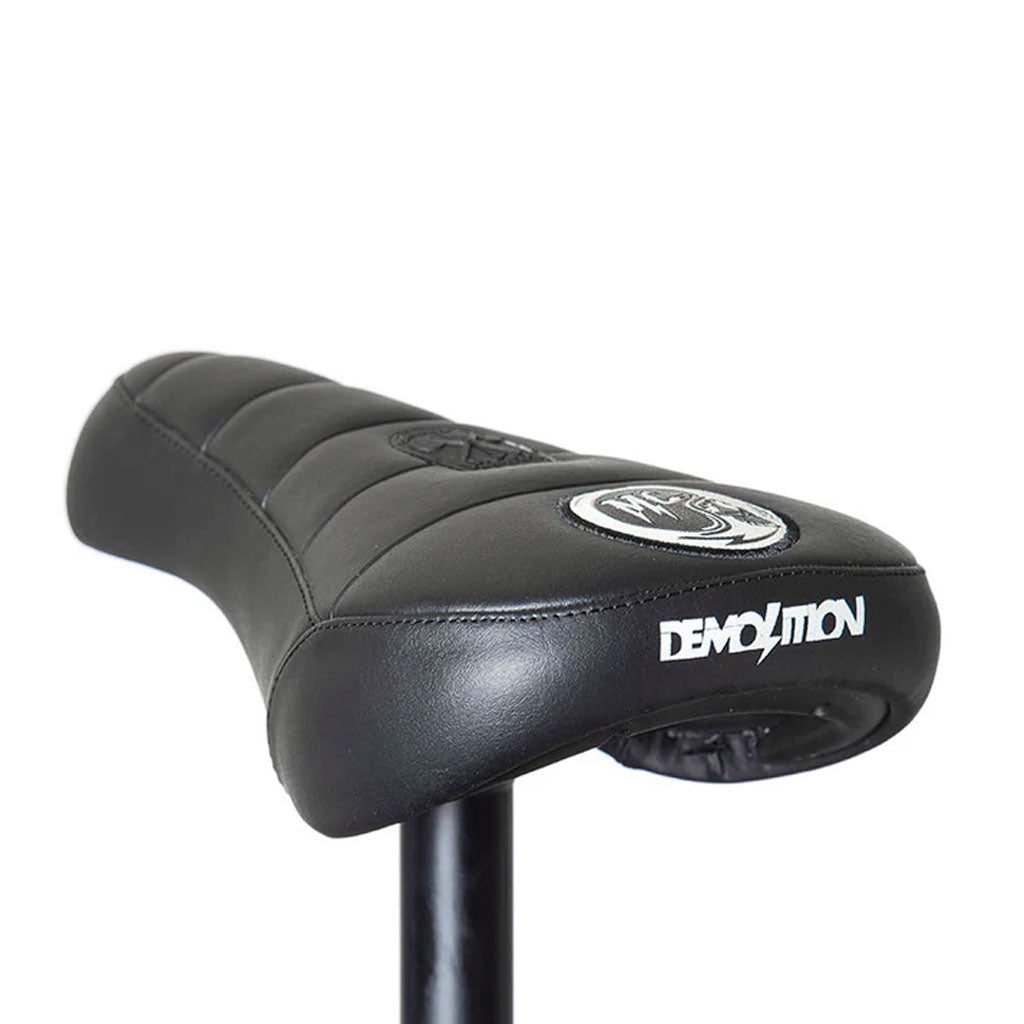 Close-up of the Demolition Matt Cordova Seat (V1) in black, featuring the "Demolition" branding on the back. This Pivotal Fat Cap design, perfect for BMX enthusiasts, offers both comfort and style for any ride.