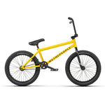 A yellow Wethepeople Justice 20 Inch Bike with black tires, a black seat, and black handlebars. The frame prominently displays "WETHEPEOPLE." This urban BMX bike features top-of-the-line components for an unparalleled riding experience.