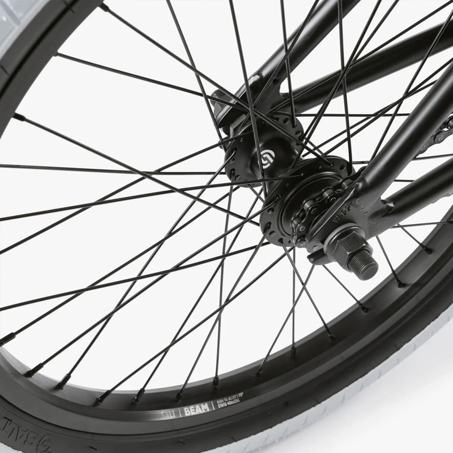 A close up of a black Wethepeople Nova 20 Inch BMX Bike wheel on a white background.