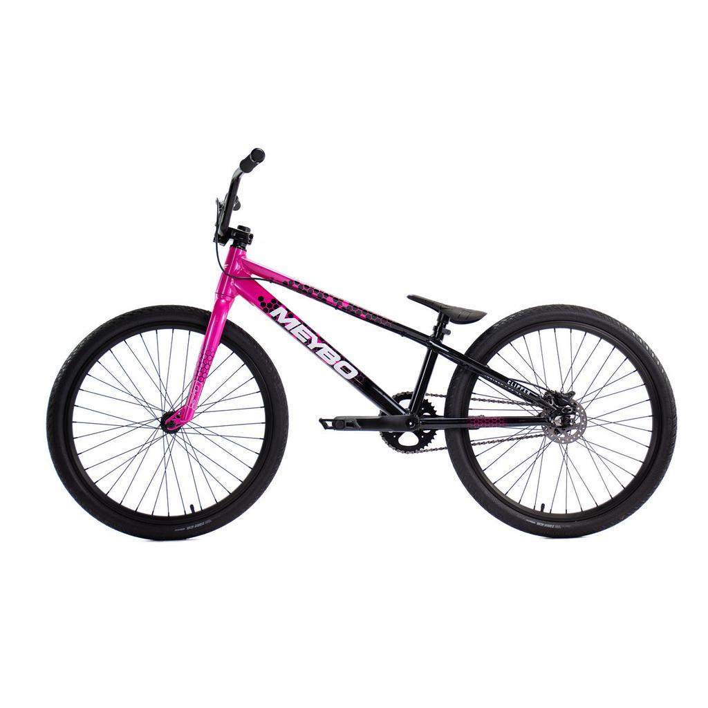 The Meybo 2026 Clipper Pro Cruiser Bike is an entry-level race BMX with a black frame, pink fork, large wheels, flat pedals, and single gear—ideal for beginners in BMX racing.