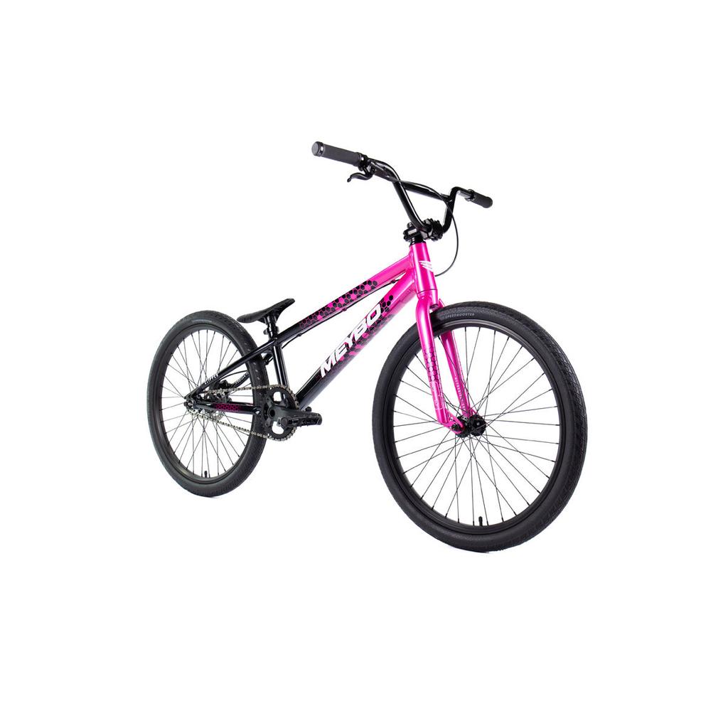 The Meybo 2026 Clipper Pro Cruiser Bike, in pink and black, features thick tires, flat handlebars, and a single gear. Shown in a photo on a white background.