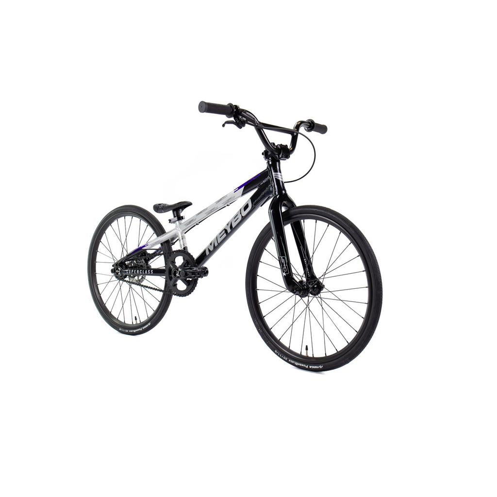 A black and white Meybo 2026 Superclass Junior BMX bike with a lightweight frame, 22” top tube, flat handlebars, and thin tires is photographed on a white background.