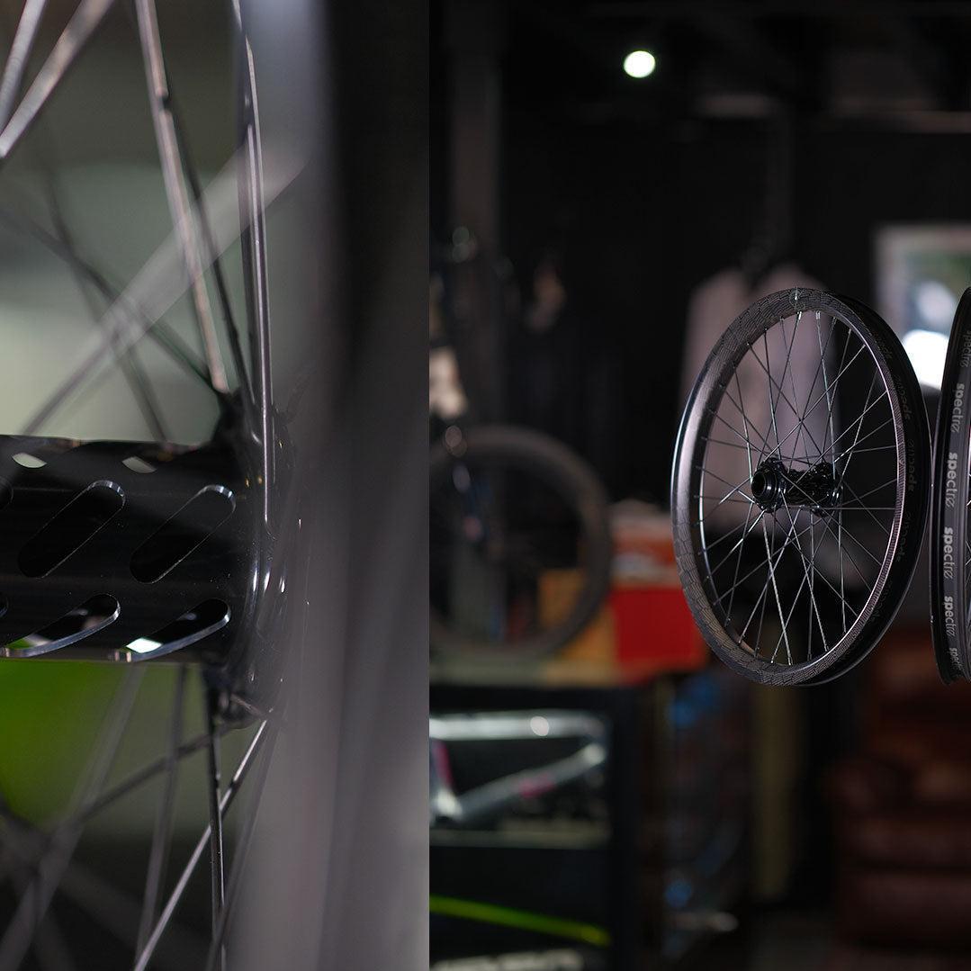 Close-up of a Spectre NME X Onyx Elite 20 Inch Disc Wheel Set (20mm/15mm) hub and spokes on the left, with the full disc wheel on the right, highlighting lightweight BMX wheels in a shop setting.