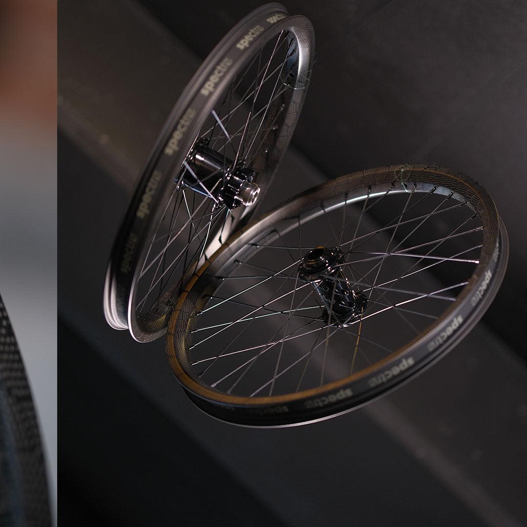 Two Spectre NME X Onyx Elite 20 Inch Disc Wheel Sets (20mm/15mm) are positioned upright against a dark background, highlighting their sleek design and lightweight build.