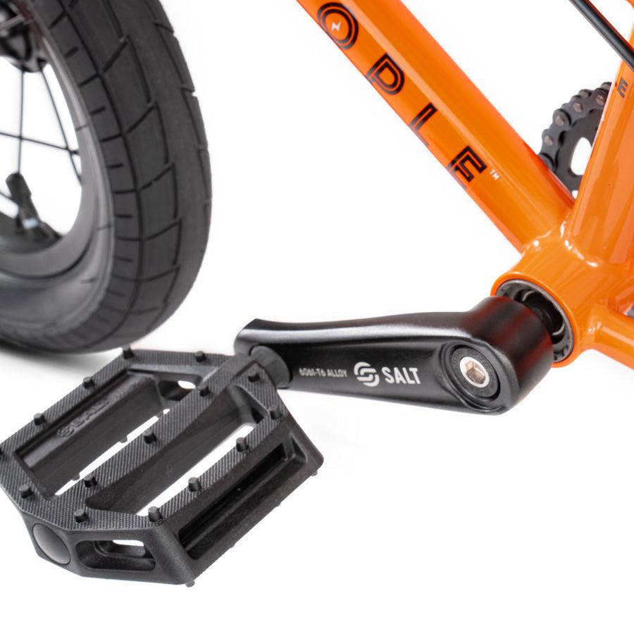 A close up image of a Wethepeople Prime Drive 12 Inch Bike with black pedals.