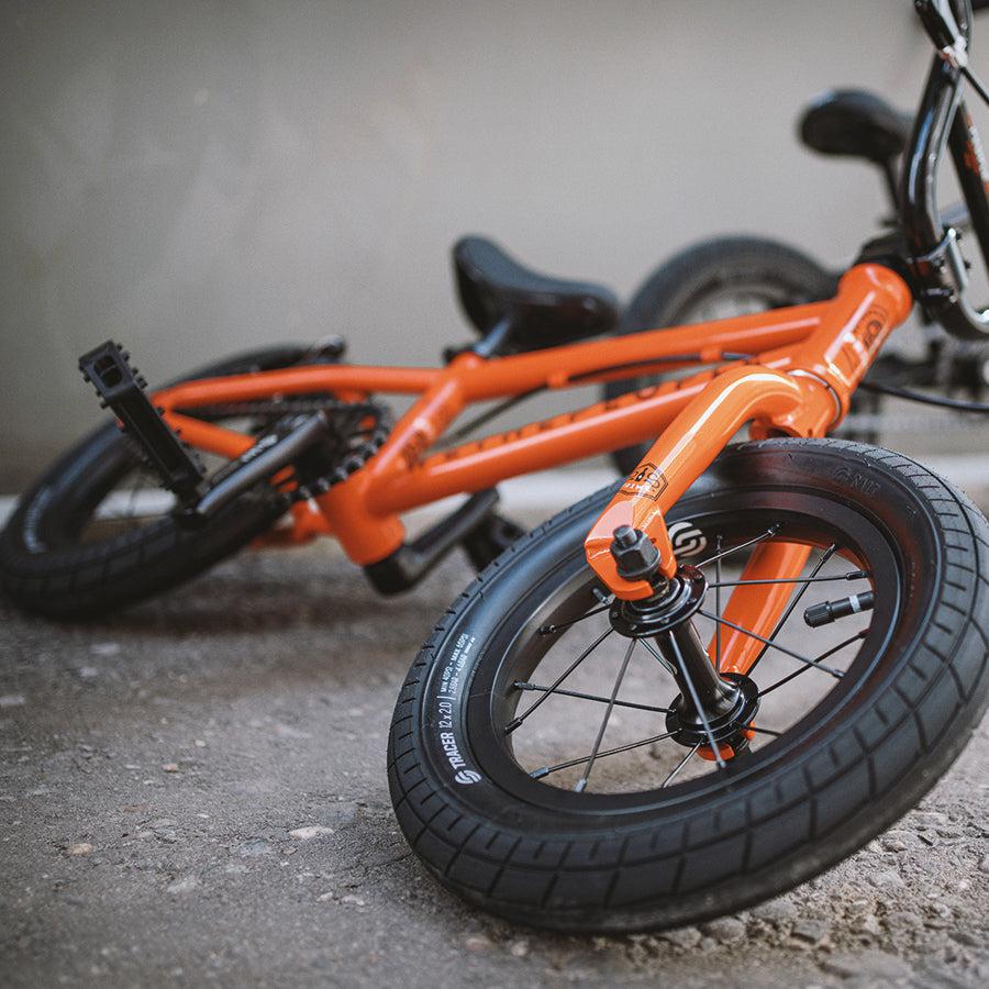 A Wethepeople Prime Drive 12 Inch Bike is parked in front of a building.