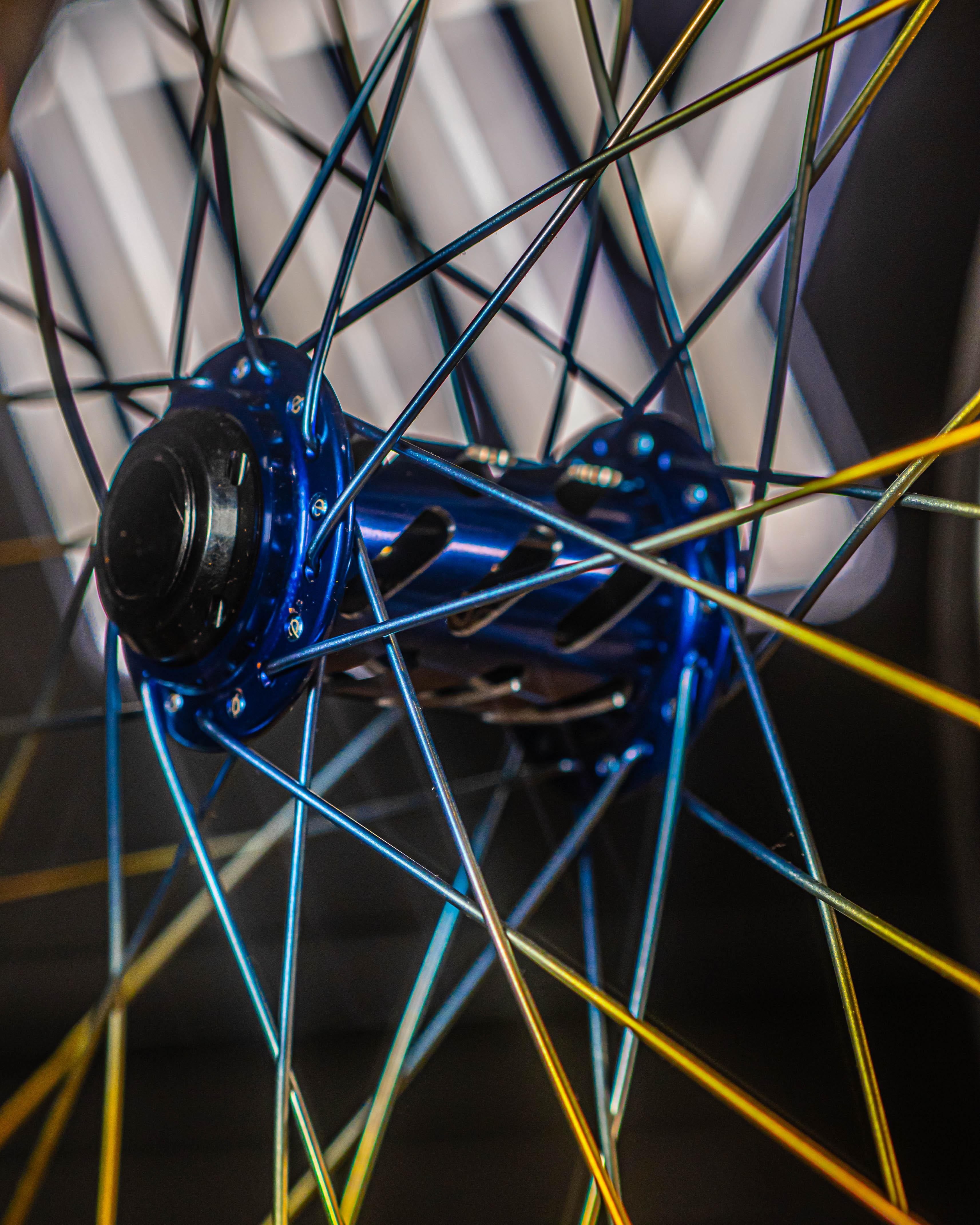 Close-up of an Onyx X Spectre Carbon Marble Sunset wheel hub with iridescent spokes and Toray T800 carbon fiber rims, set against a blurred background.