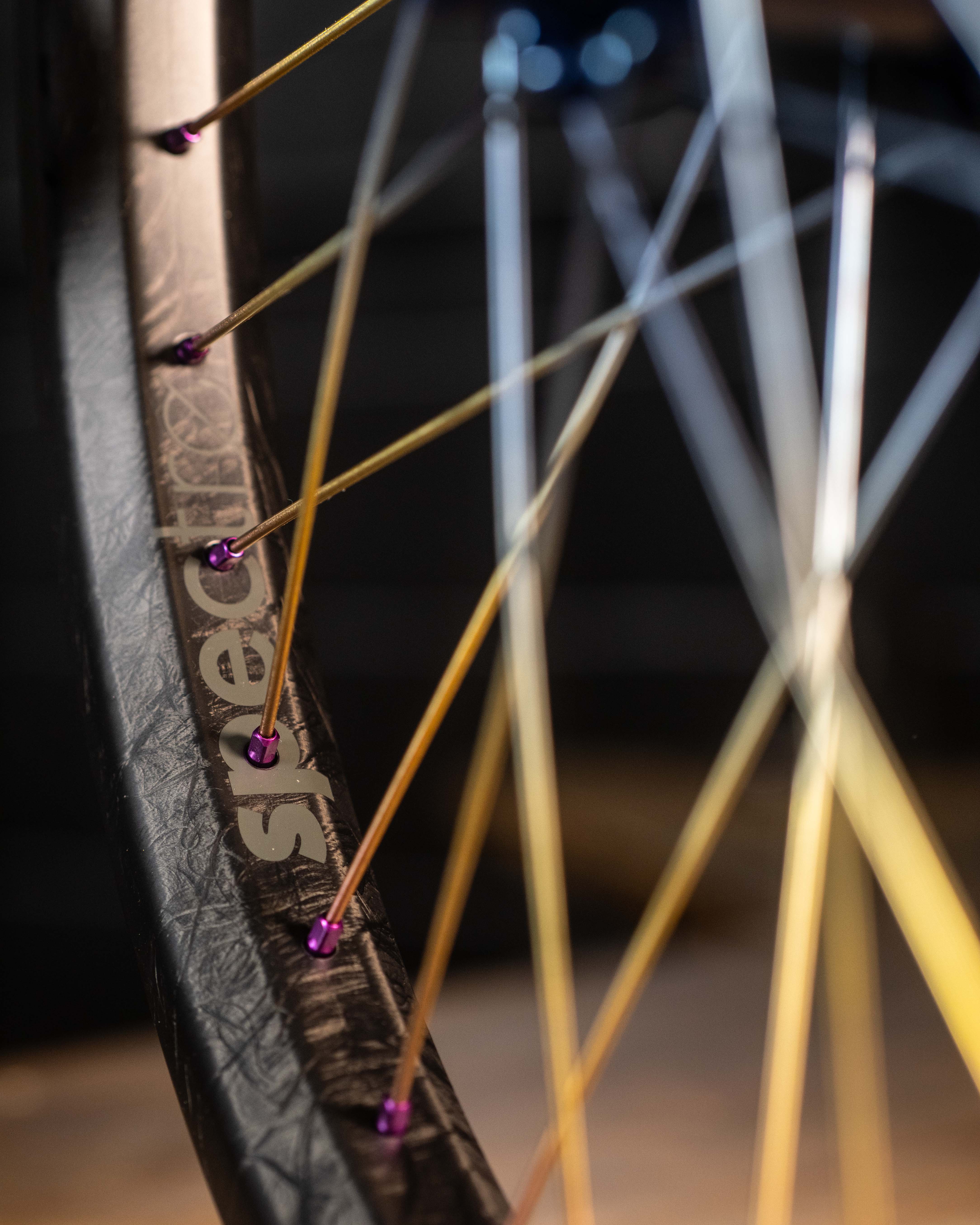 Close-up of an Onyx X Spectre Carbon Marble Sunset 20-inch wheelset, highlighting colorful spokes on a sleek black rim with premium Toray T800 carbon fiber and the "spectre" brand name.