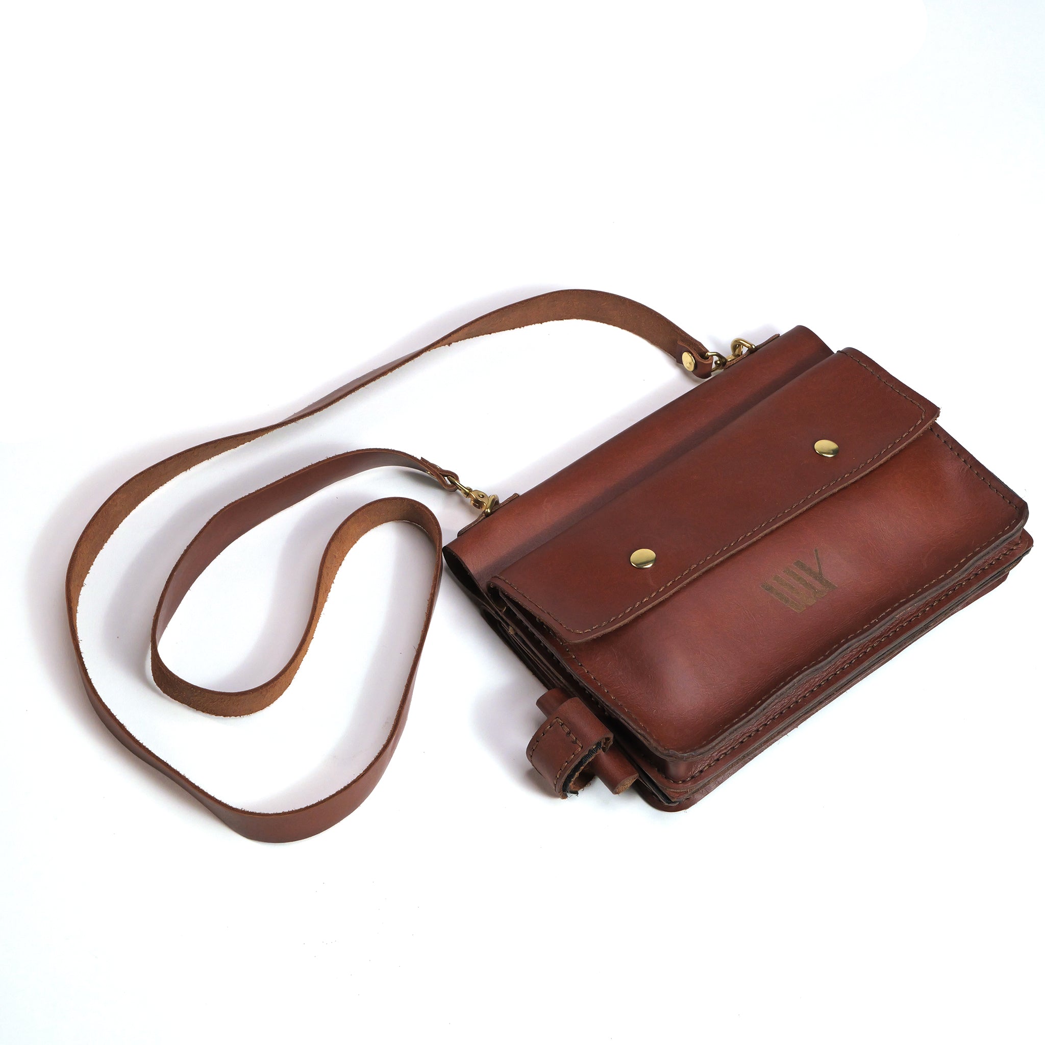The LUXBMX Deluxe Leather Frame Bag is handcrafted from brown full-grain leather, features a long adjustable strap, a front flap with two gold snaps, and a subtle embossed logo for timeless style and quality.