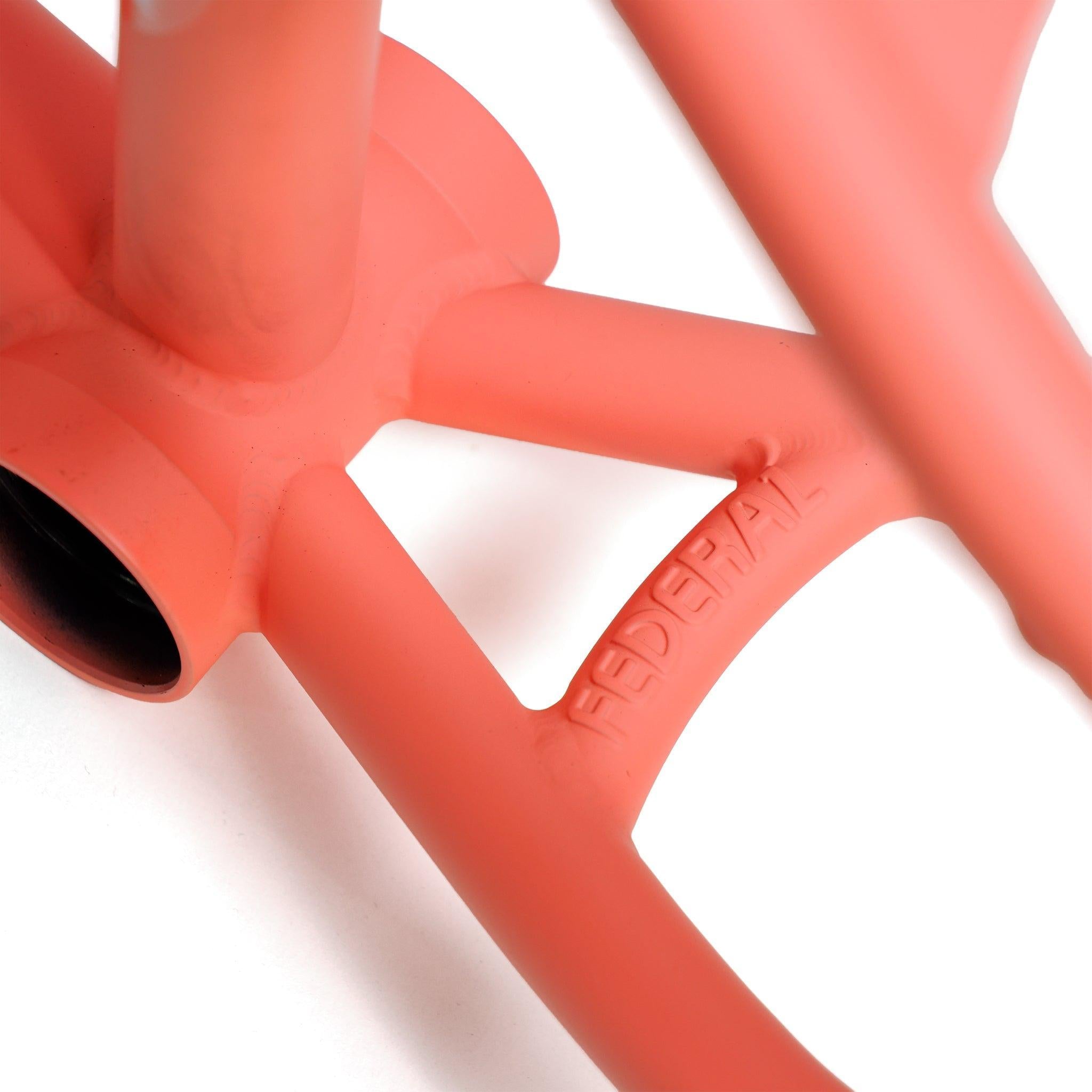 Close-up of the matte coral Federal Lacey 3 Frame, made from 4130 Chromoly tubing, featuring "FEDERAL" embossed on the rear triangle near the bottom bracket.