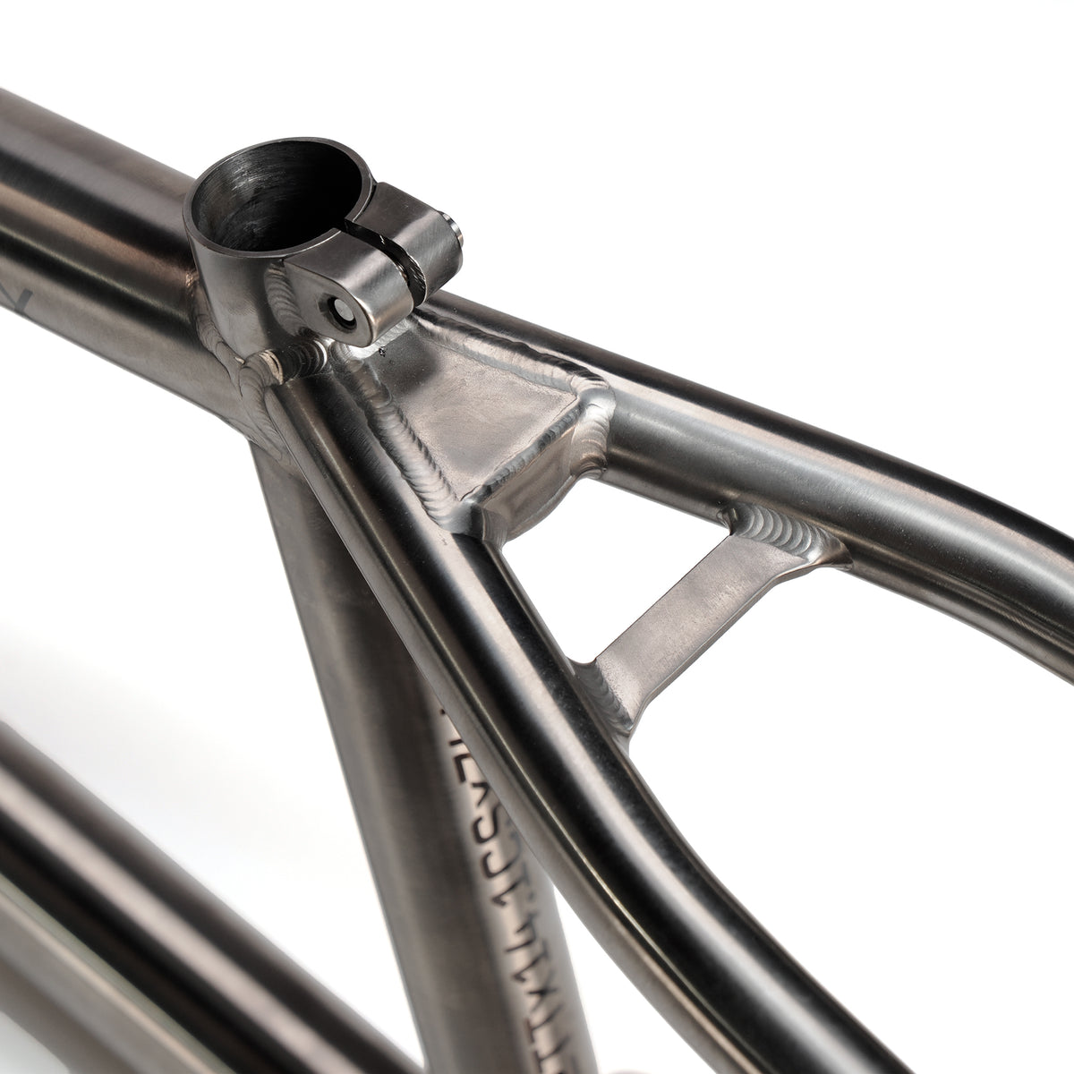 Close-up of the ION BMX Ti22 Titanium 22 Inch Frame showing the seat tube junction, precise welds, and seat post clamp against a white background. Features CS-14.1 geometry for advanced performance.