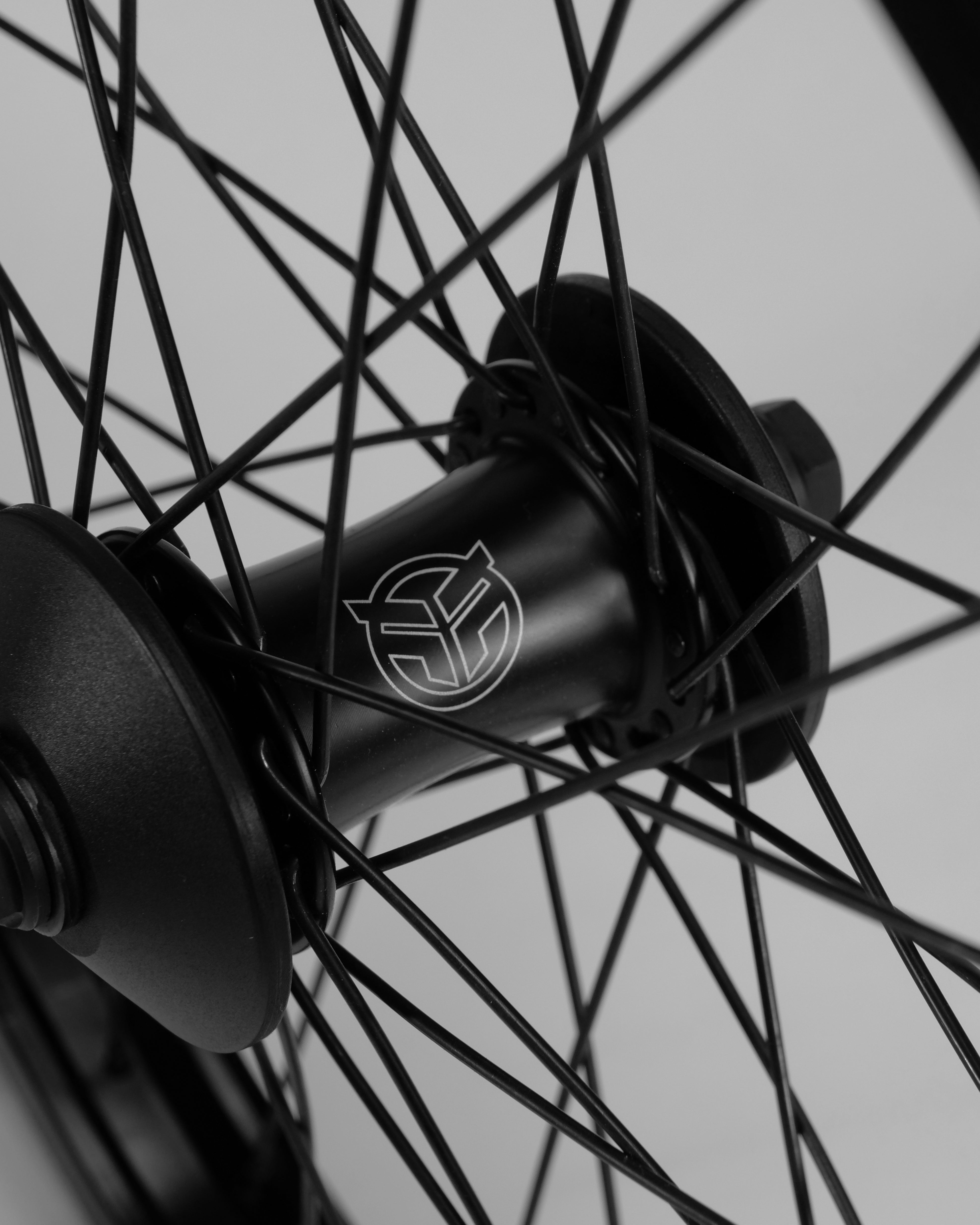 Close-up of a black bicycle wheel hub with intricate spokes, featuring a Federal Stance Pro x Alienation 18 Custom Wheelset logo.