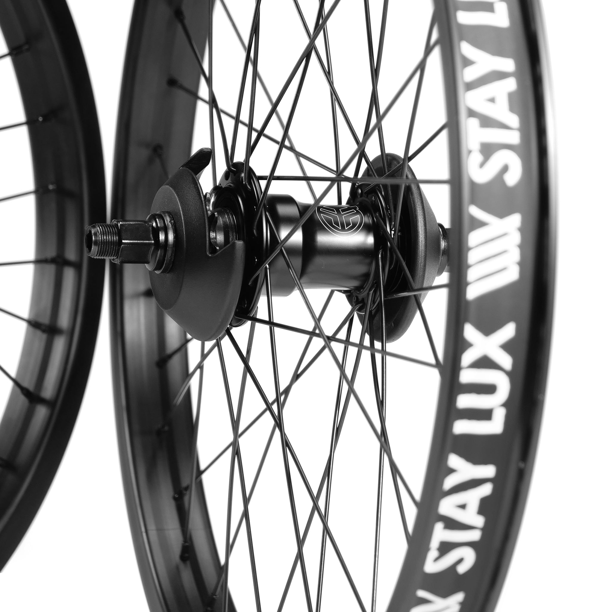 Close-up of two black bicycle wheels with spokes, featuring the hubs and axles. The rims have text that reads "STAY LUX". These could be part of a Federal Motion x Odyssey Stage 2 Custom Wheelset, ideal for tricks and stunts like those pulled off by Boyd Hilder.