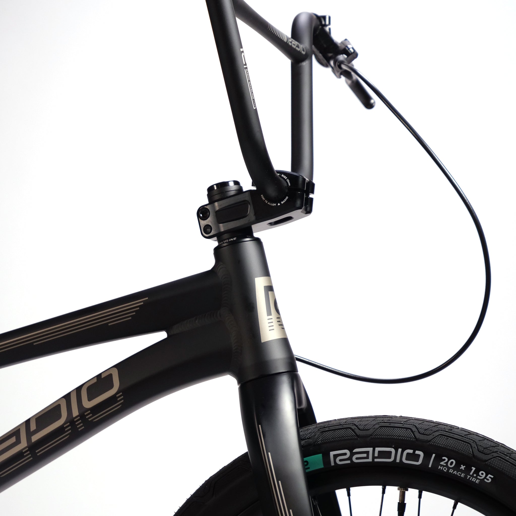 Close-up of a black Radio Raceline Quartz Pro L Bike 2025's front frame and handlebars, showcasing the brand name "Radio" on the lightweight hydro-formed frame and tire against a plain white background.