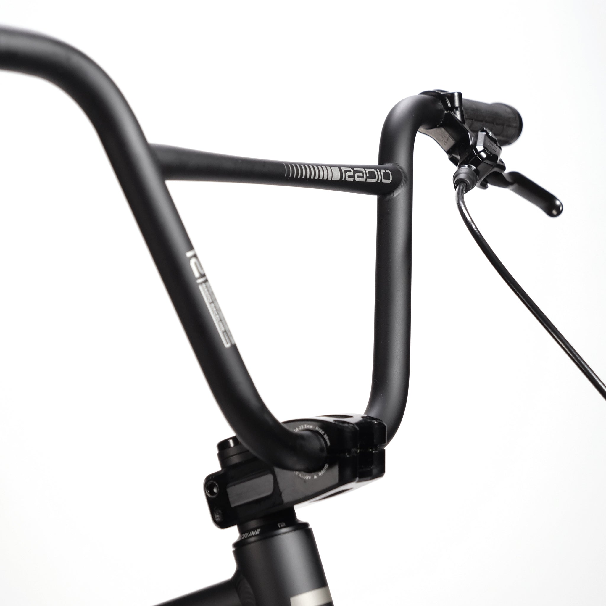 Close-up of black bicycle handlebars with Radio branding, brake lever, and cables against a plain white background. The sleek design complements the lightweight hydro-formed frame and hydraulic disc brakes of the Radio Raceline Quartz Pro L Bike 2025 for a smooth ride.