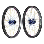 Two Onyx X Spectre Carbon Marble Sunset 20-inch wheels with sleek black rims and blue hubs showcase striking titanium spokes in gold and silver, displayed against a pristine white background.