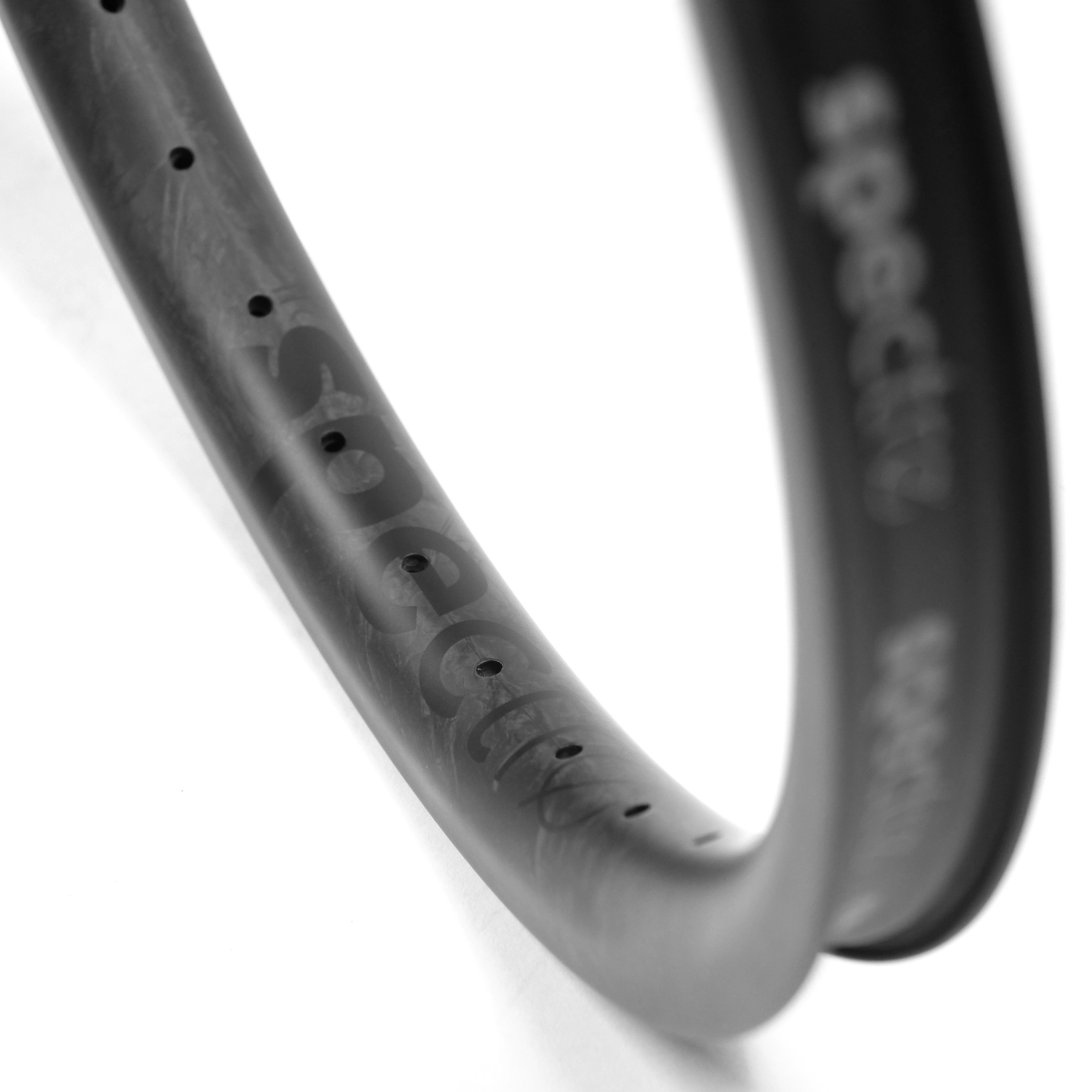 Close-up of the Spectre V3 Carbon Fiber 20 Inch 36H Brakeless Rim, showing its curved matte-black finish, evenly spaced 4D drilled holes, and subtle "spectre" branding on the surface.