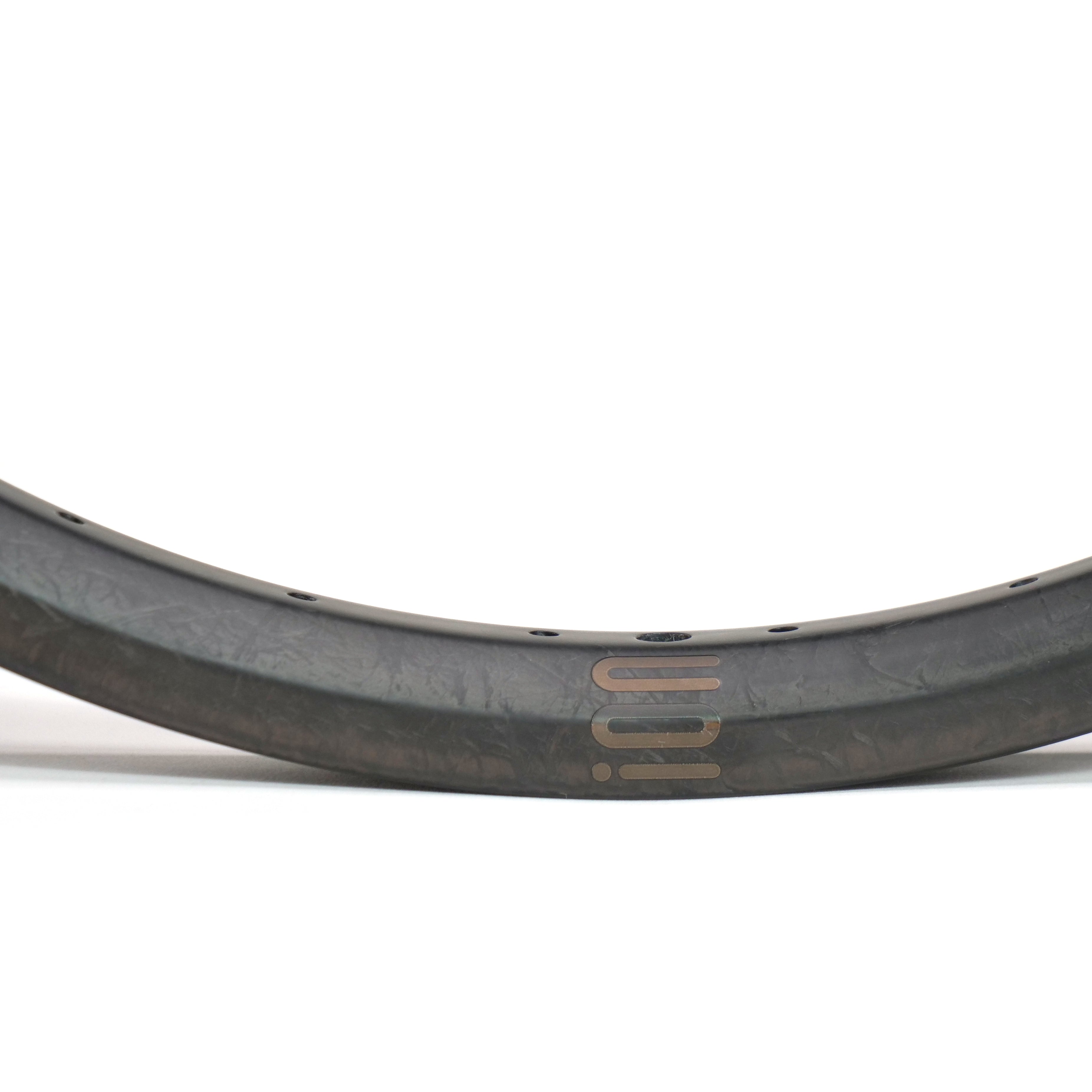 A close-up of the ION BMX C22 Carbon Fiber 22 Inch Brakeless Rim, showcasing its curved matte finish, multiple spoke holes, and minimal branding.