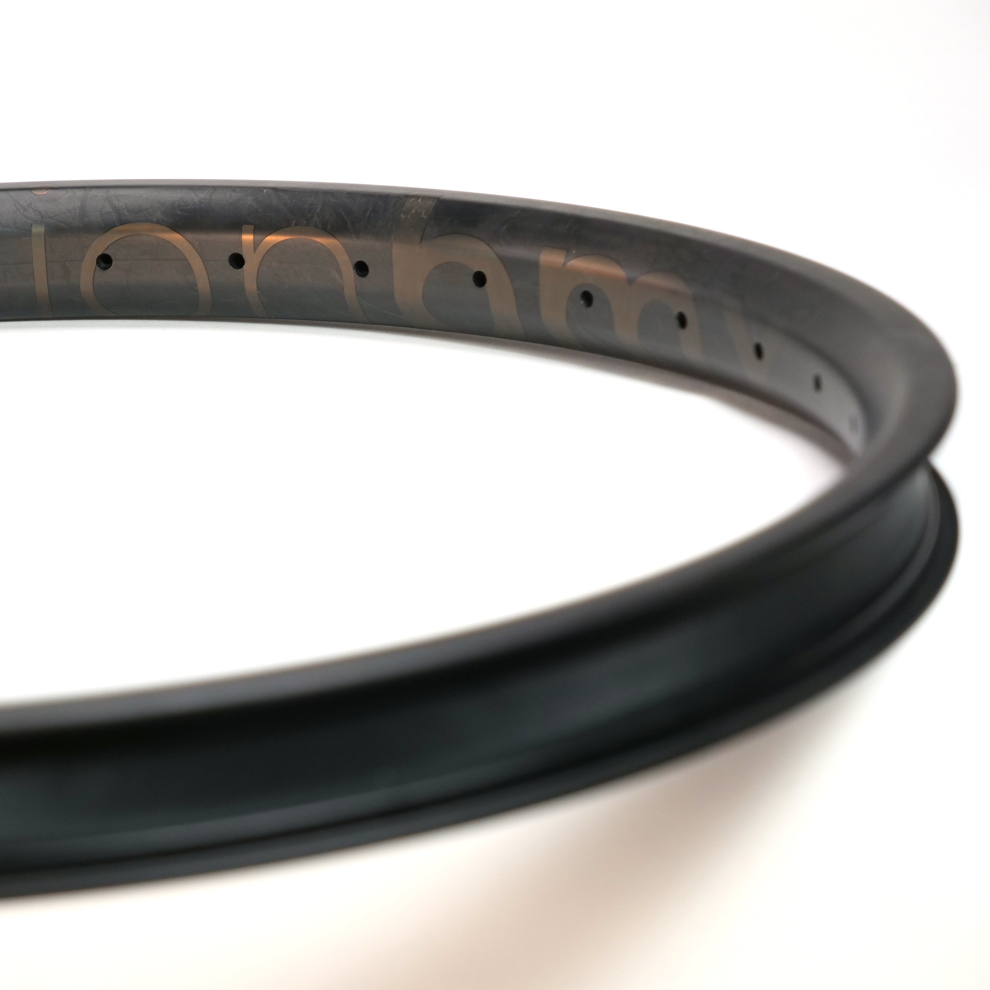 Close-up of the ION BMX C22 Carbon Fiber 22 Inch Brakeless Rim in black with multiple spoke holes against a white background, highlighting its lightweight BMX design.