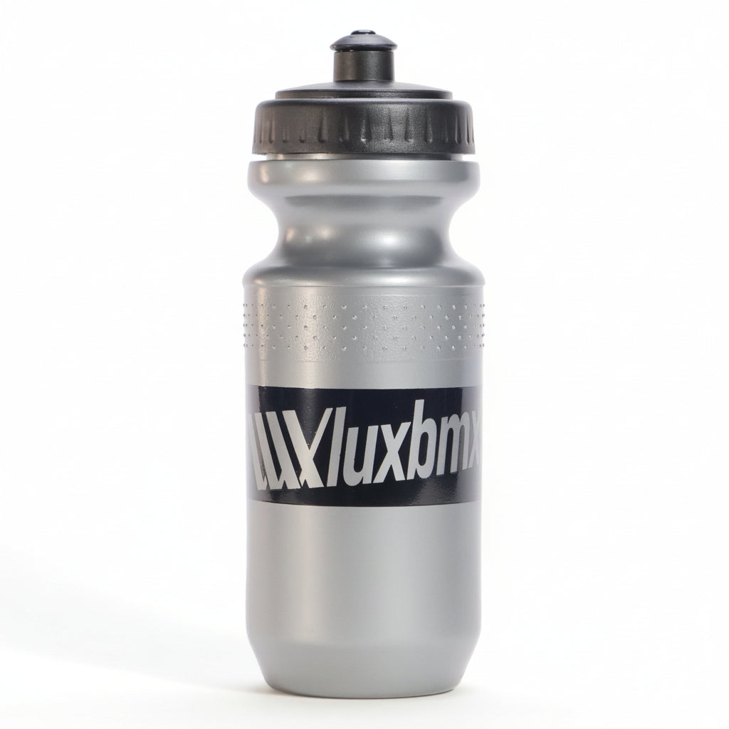 The LUXBMX Squirt Water Bottle 500ml is silver, made from BPA-free plastic, and features a black screw cap and spout. Bold "Luxbmx" lettering stands out on its side.