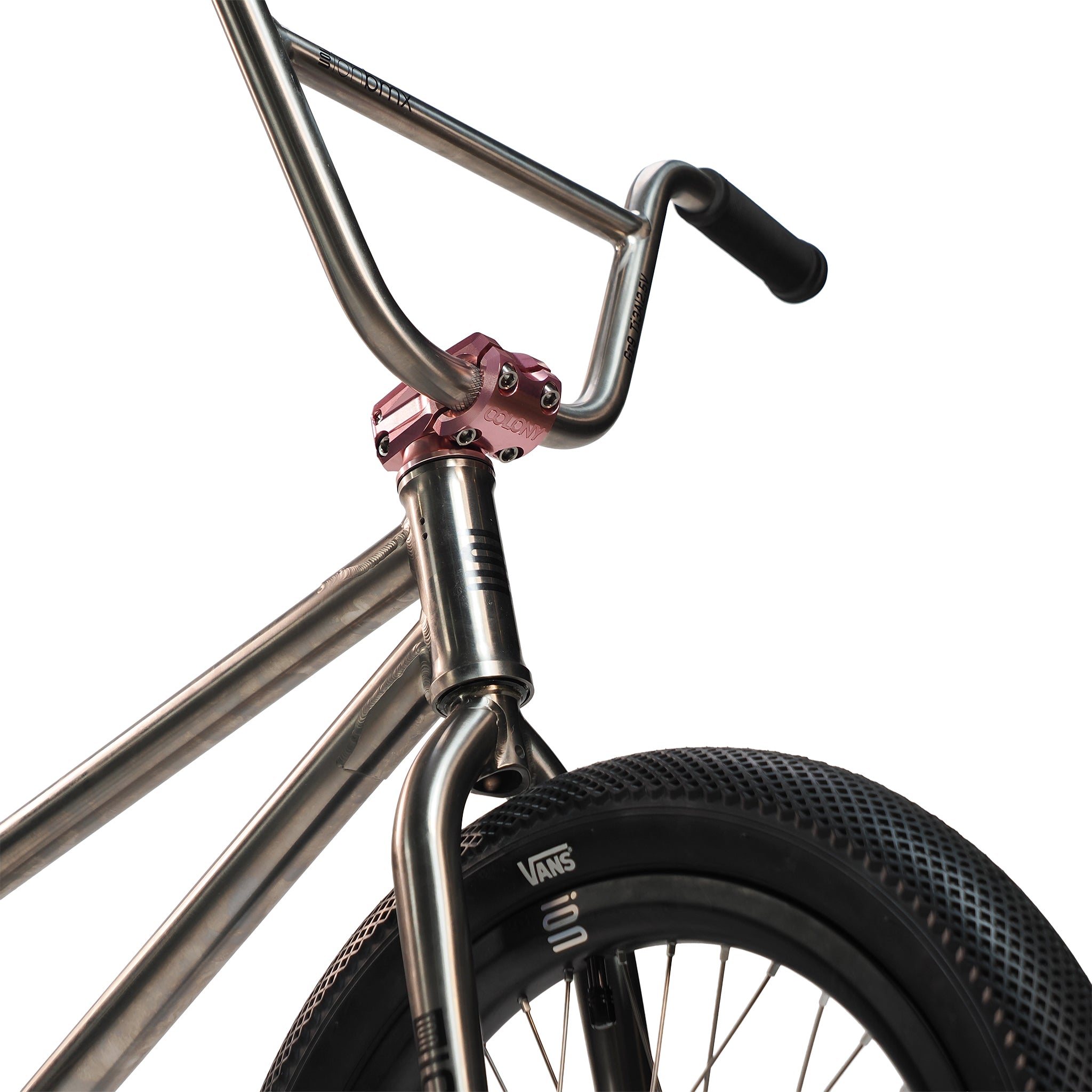 Close-up of an ION BMX Ti18 Custom Titanium 18 Inch Bike, featuring lightweight handlebars with a pink stem, a front tire with “Vans” branding, and a metallic frame, all set against a white background.