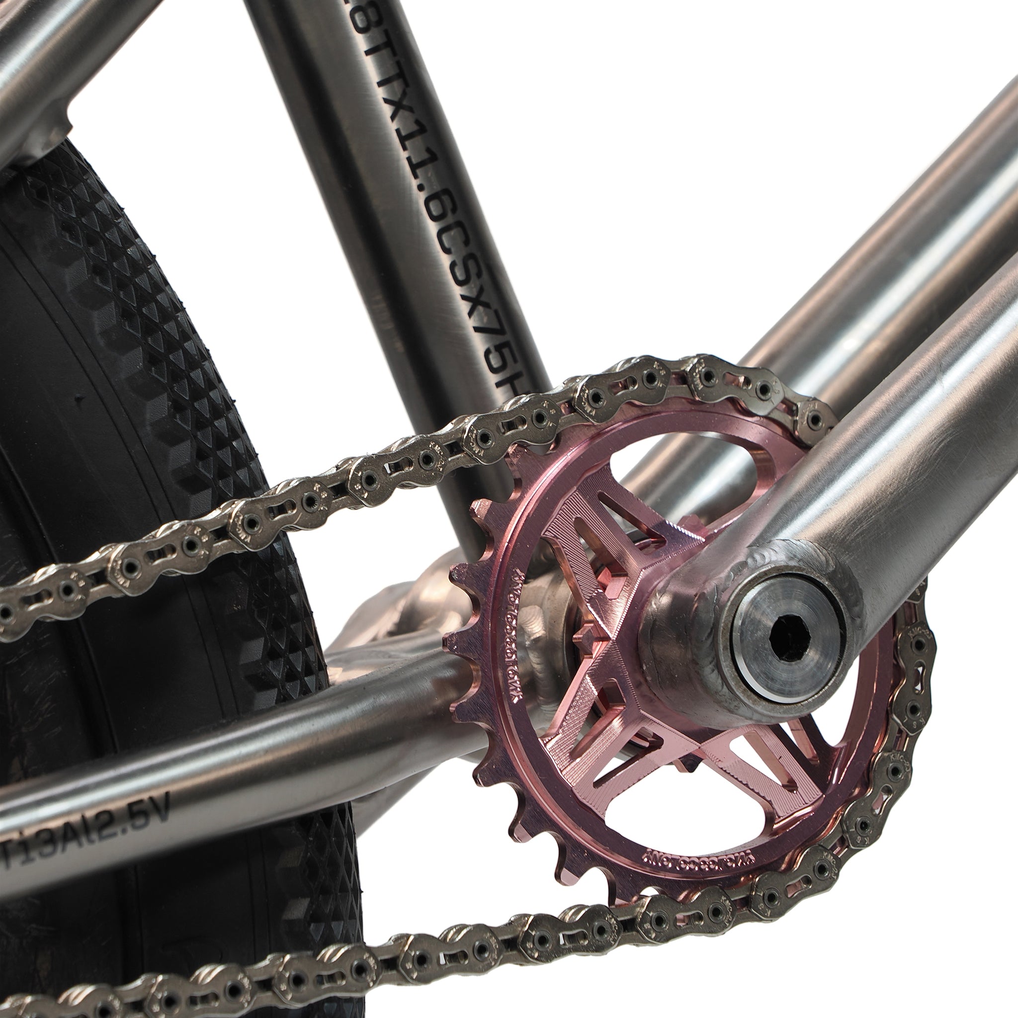 Close-up of the chain, rear wheel, and metallic pink sprocket on an ION BMX Ti18 Custom Titanium 18 Inch Bike—a lightweight option ideal for freestyle BMX riding.