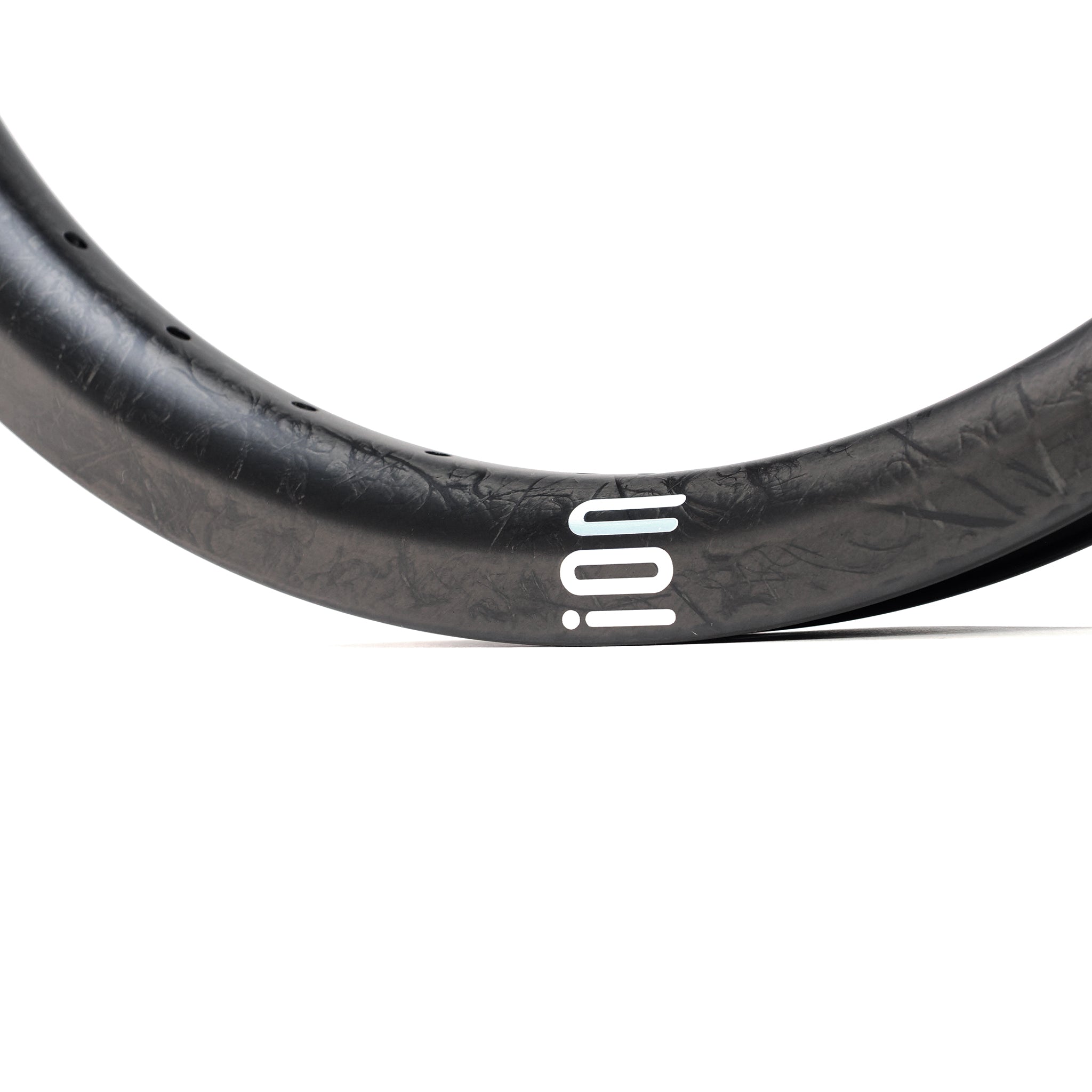 Close-up of the ION BMX C18 Carbon Fiber 18 Inch Brakeless Rim in black, featuring a subtle textured Toray T800s carbon fiber pattern and "ion" printed in white lowercase letters.