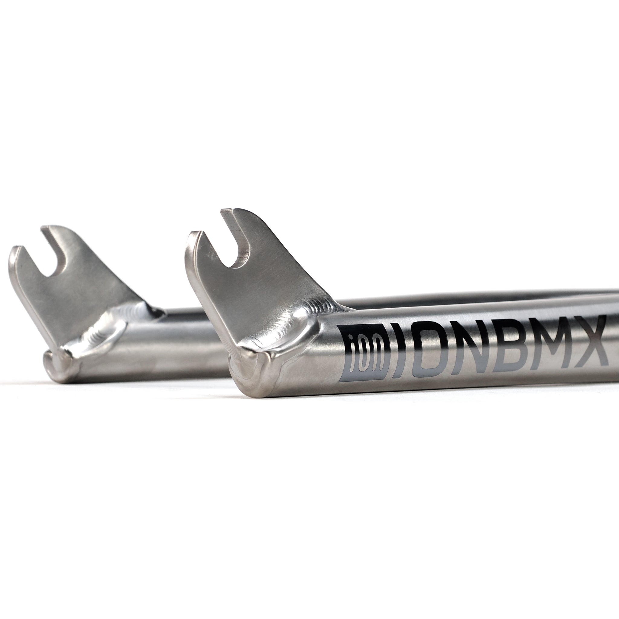 Close-up of two metallic dropouts with visible welds on the ION BMX Ti18 Titanium 18 Inch Forks, featuring the engraved "IONBMX" logo.