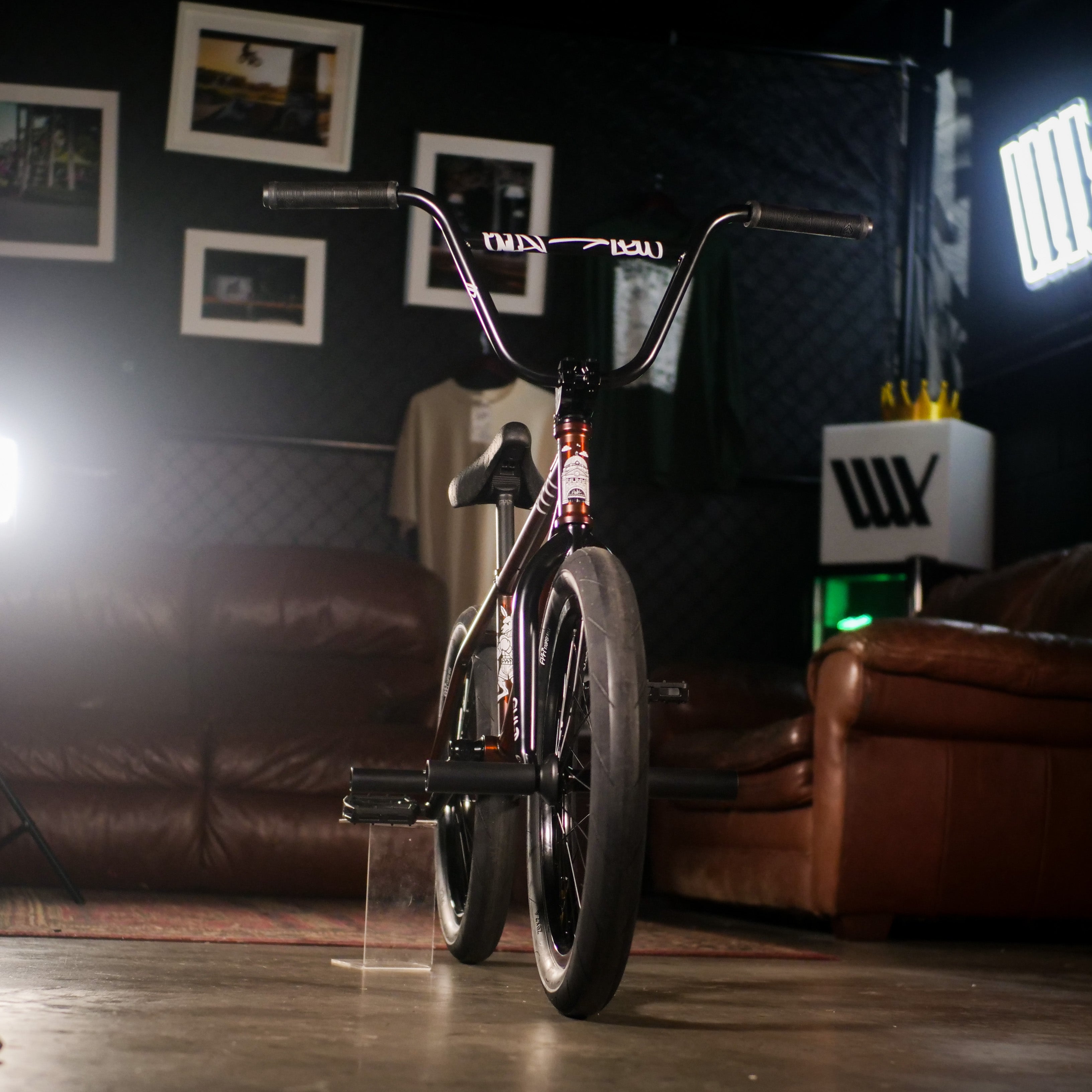 The Cult Dak X Eclat Custom 'Pat Freyne Signature' BMX bike is displayed indoors on a concrete floor, with sofas, framed pictures, and spotlights in the background.