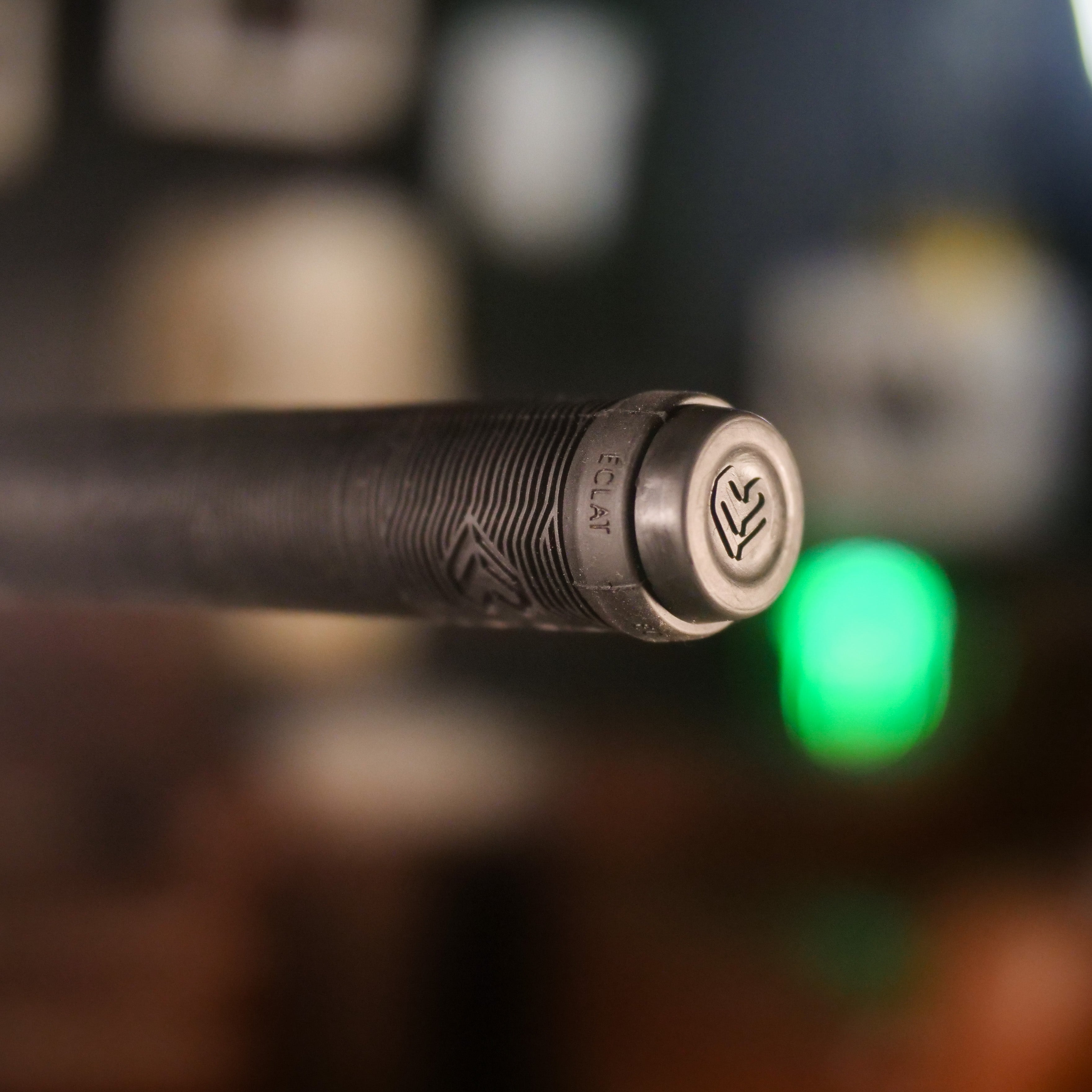 Close-up of the end of a textured black Cult Dak X Eclat Custom 'Pat Freyne Signature' BMX handlebar grip with a logo and "ECLAT" engraved on the metal end cap.