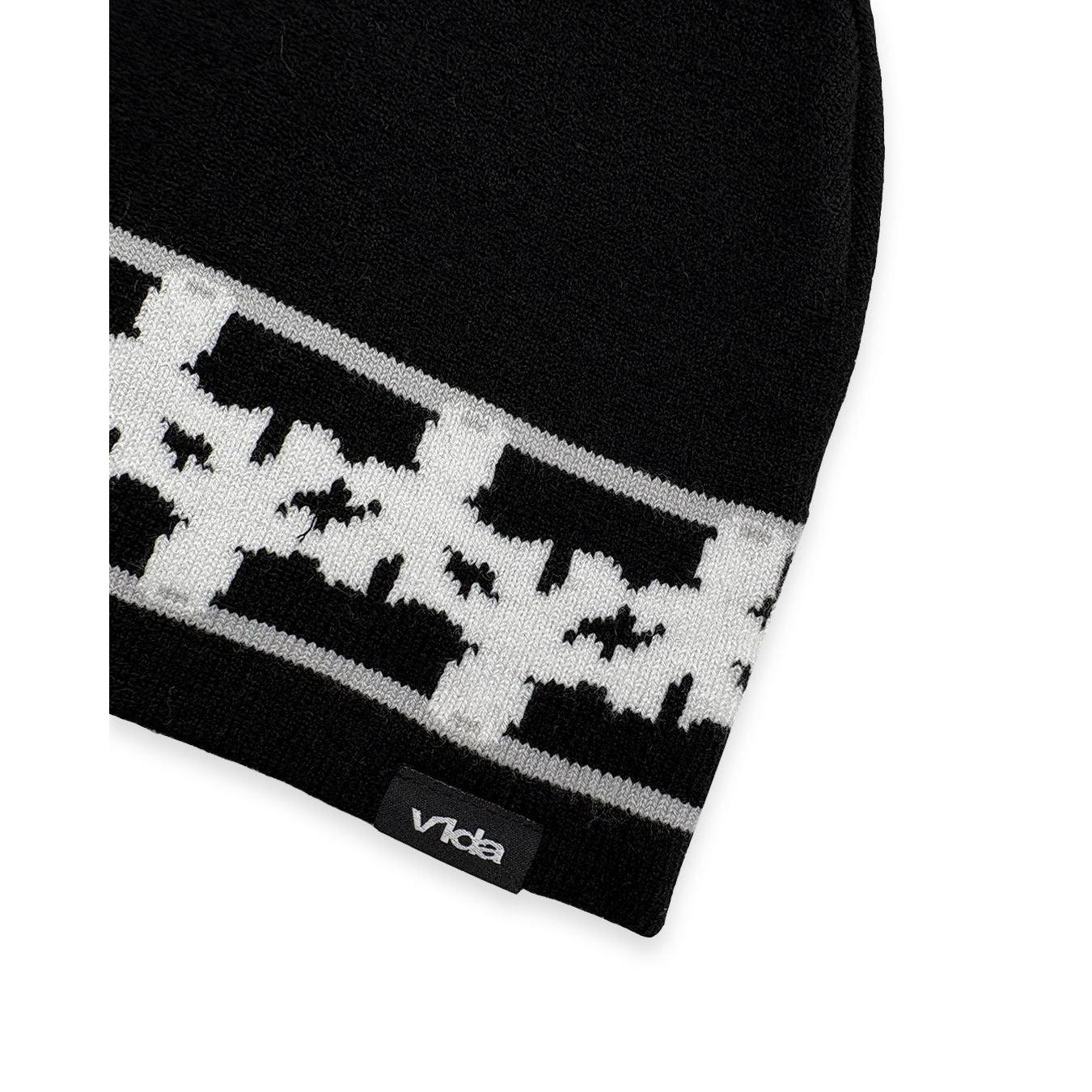 The V1da Pattern Beanie is a black skully hat with a white geometric design and a subtle black tag featuring "Vida" near the edge—ideal for stylish winter wear.